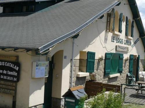 a building with green shutters and a sign on it at Le Logis Catalan - Gîte de groupe et familial in Font-Romeu