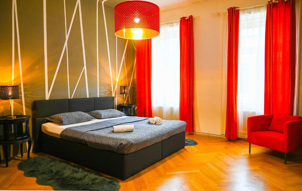 ein Schlafzimmer mit einem Bett und einem roten Stuhl in der Unterkunft Highlight Suite City Center in Wien