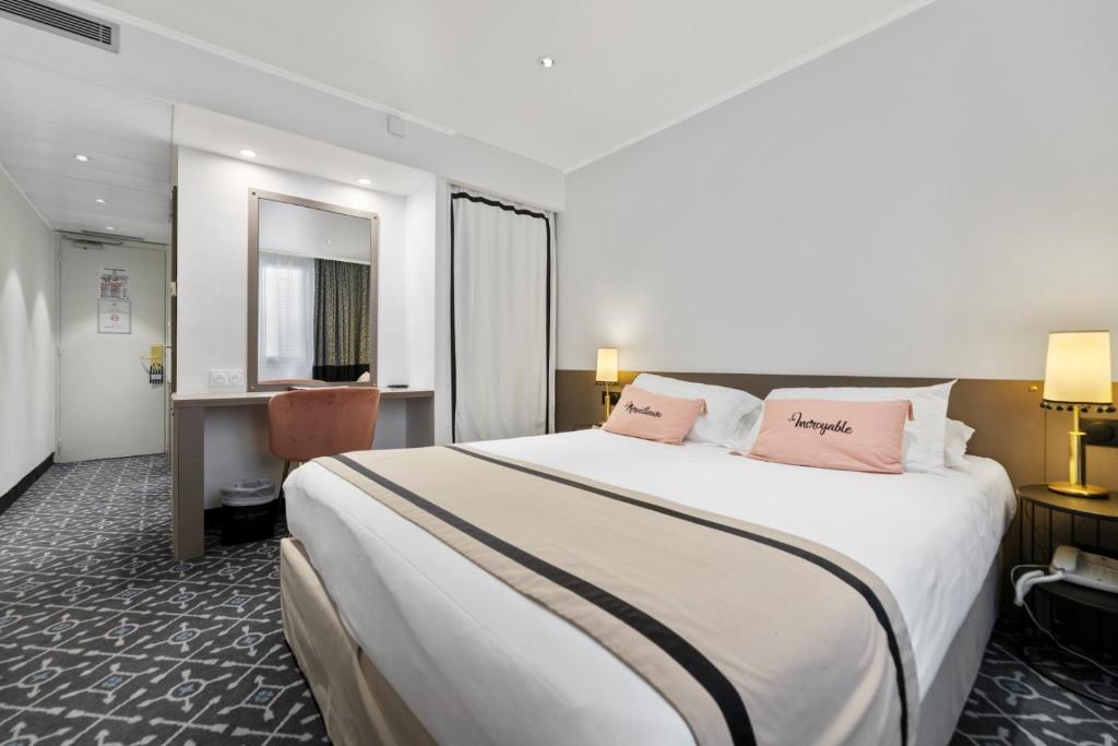 a hotel room with a large bed with pink pillows at Napoleon in Ajaccio
