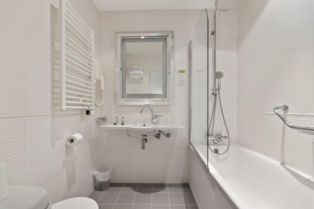 a white bathroom with a tub and a sink and a toilet at Napoleon in Ajaccio