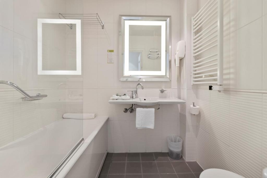 a white bathroom with a sink and a tub and a toilet at Napoleon in Ajaccio