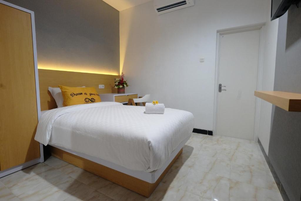 1 dormitorio con cama blanca y almohada amarilla en Gapura Residence Airport Semarang by Sinergi en Semarang