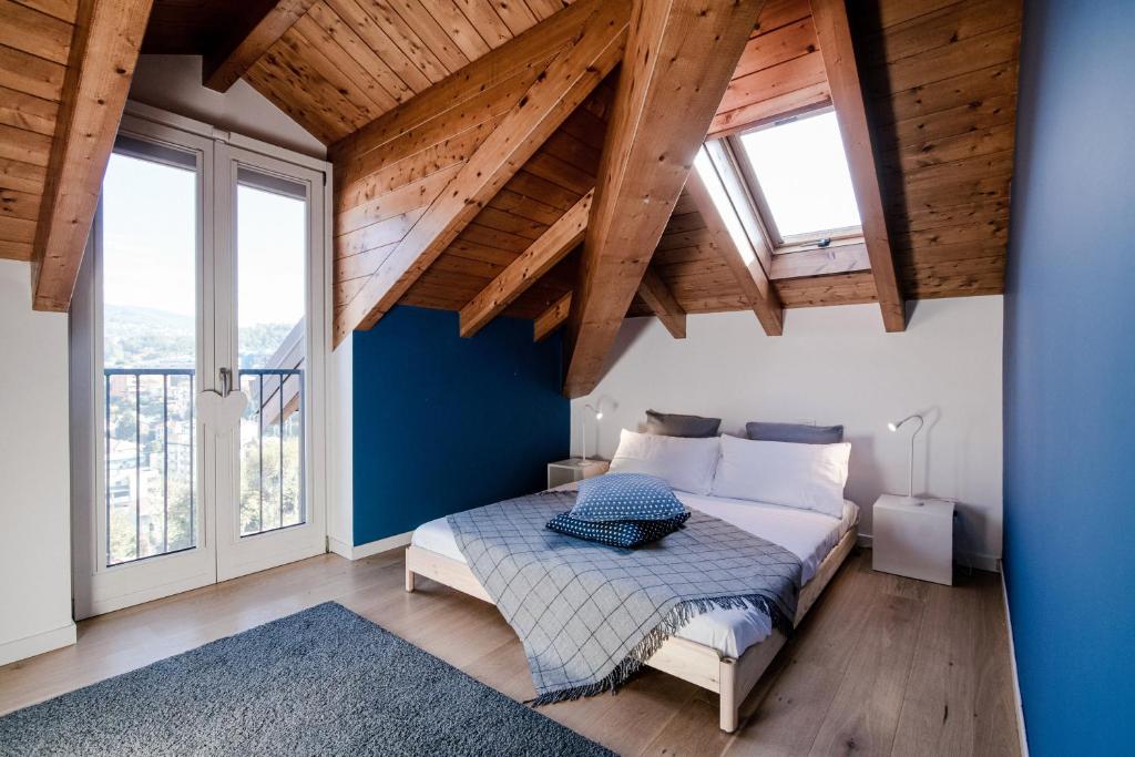 - une chambre dotée d'un lit avec des murs bleus et des plafonds en bois dans l'établissement Modern Luxury Attic - byMyHomeInComo, à Côme