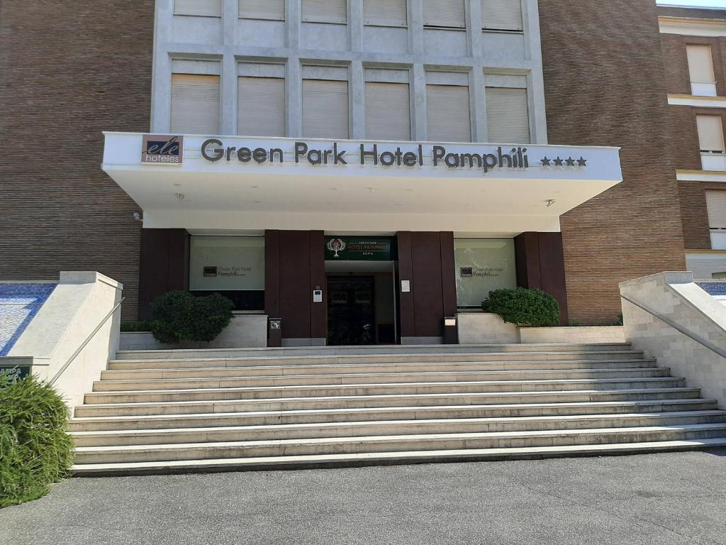 ローマにあるEle Green Park Hotel Pamphiliの緑豊かな公園ホテルのピラミッドへ続く階段のある建物