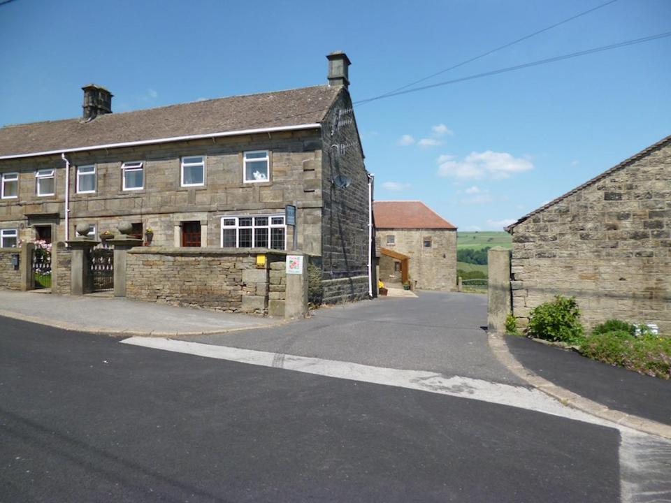 an old stone building with a road in front of it at Padley Farm in Bradfield