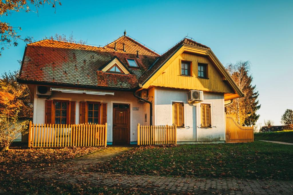 una casa amarilla y blanca con una valla en Sunny apartment, en Moravske Toplice