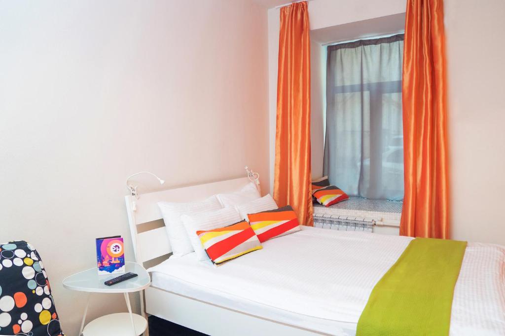 1 dormitorio con 1 cama y una ventana con cortina naranja en Station Hotel G73, en San Petersburgo