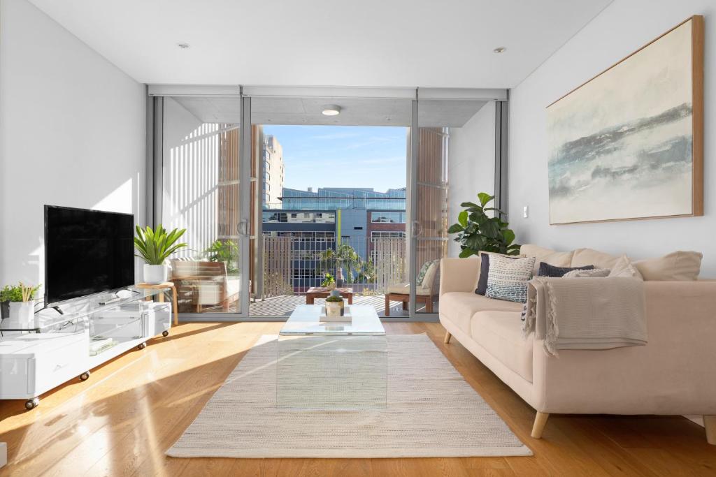 un soggiorno con divano e una grande finestra di Waterloo St Apartments by Urban Rest a Sydney