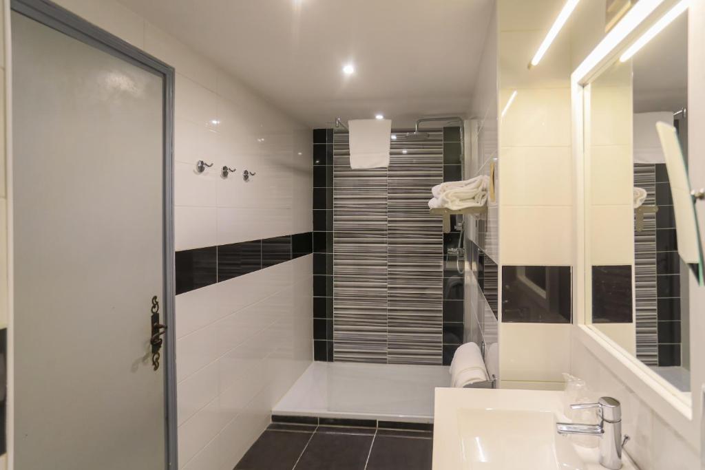 a white bathroom with a shower and a sink at Hôtel Spunta Di Mare in Ajaccio