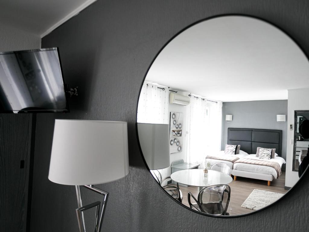 a mirror reflecting a living room with a table and a couch at Hôtel Spunta Di Mare in Ajaccio