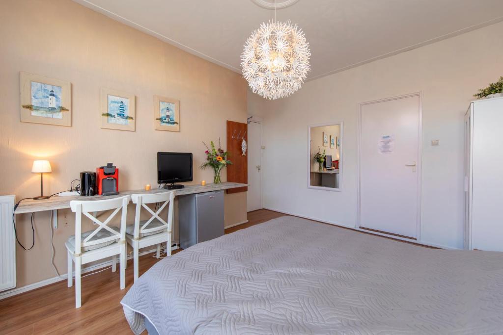1 dormitorio con cama, escritorio y lámpara de araña en Blankebil Rooms en Zandvoort