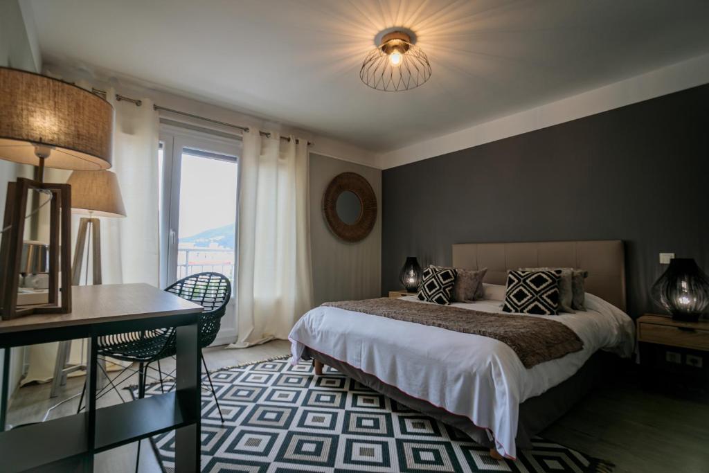 a bedroom with a bed and a desk and a window at Hôtel Spunta Di Mare in Ajaccio