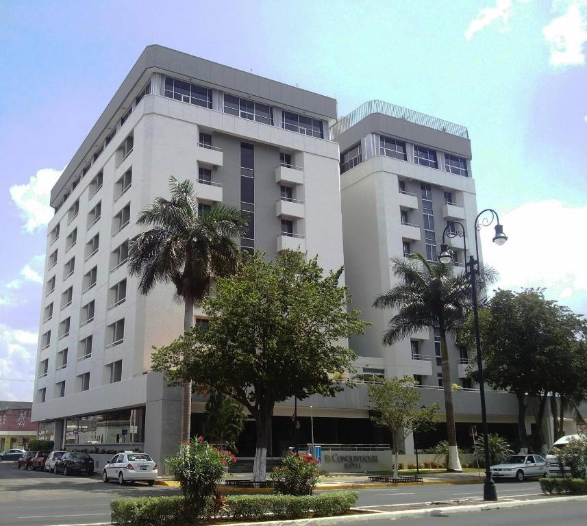 a white building with palm trees in front of it at Hotel El Conquistador del Paseo de Montejo in Mérida