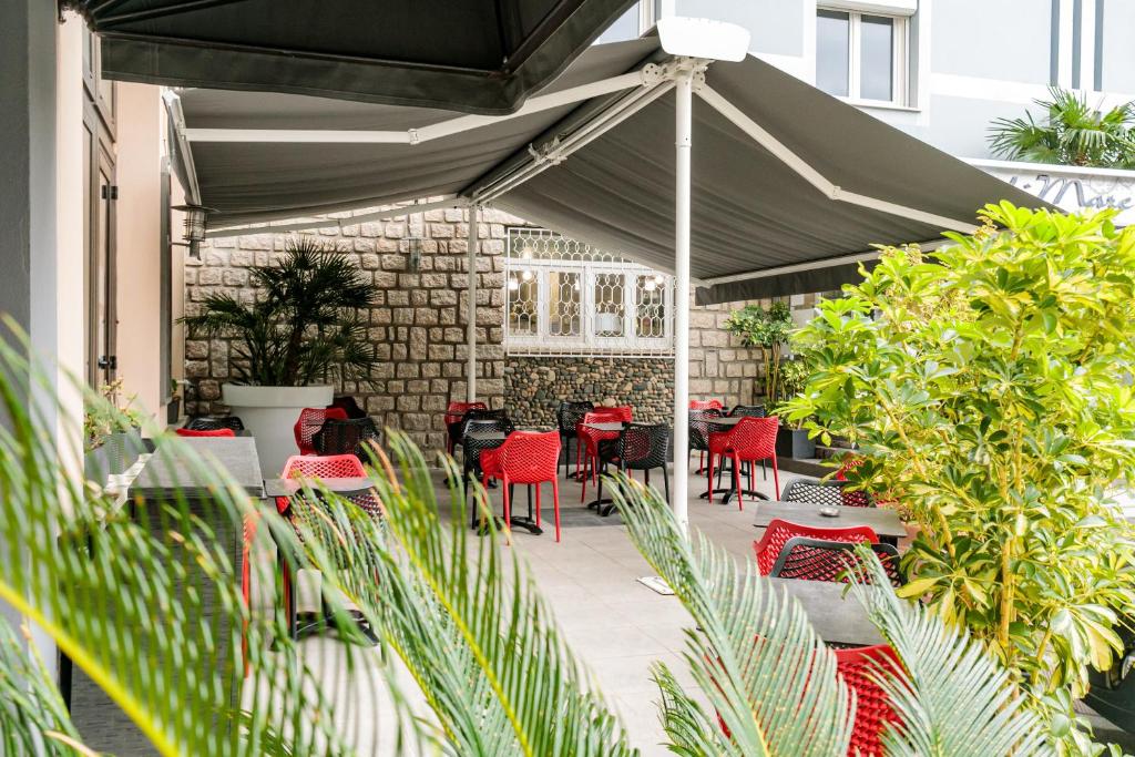 a patio with tables and chairs under an umbrella at Hôtel Spunta Di Mare in Ajaccio