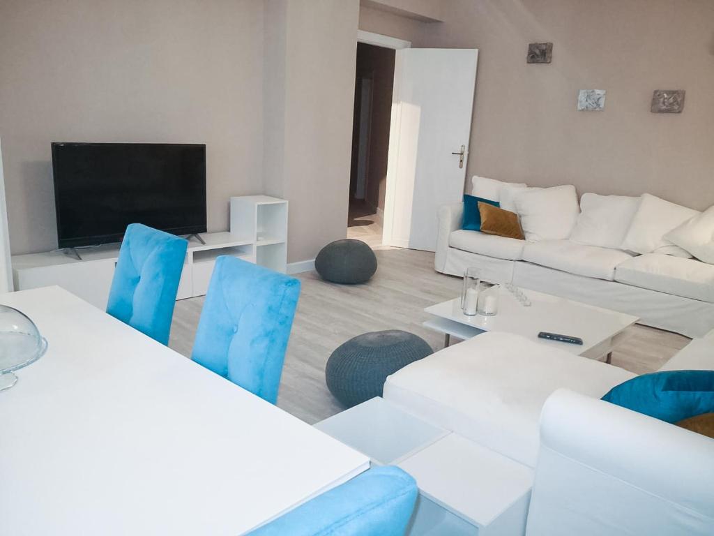 sala de estar con muebles blancos y sillas azules en La casa di Fabia - Home suite, en Messina