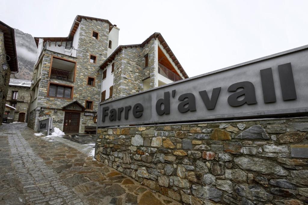 un cartel en una pared de piedra junto a un edificio en Hotel Farré D'avall, en Barruera