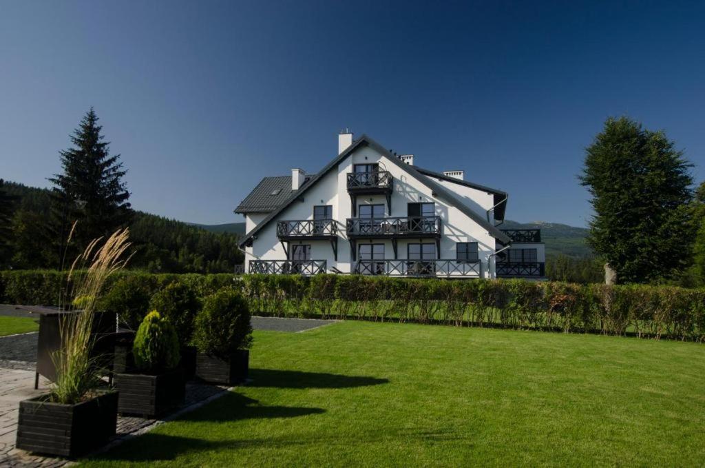 une grande maison blanche avec une pelouse devant elle dans l'établissement Villa Hotelu Seidorf, à Sosnówka