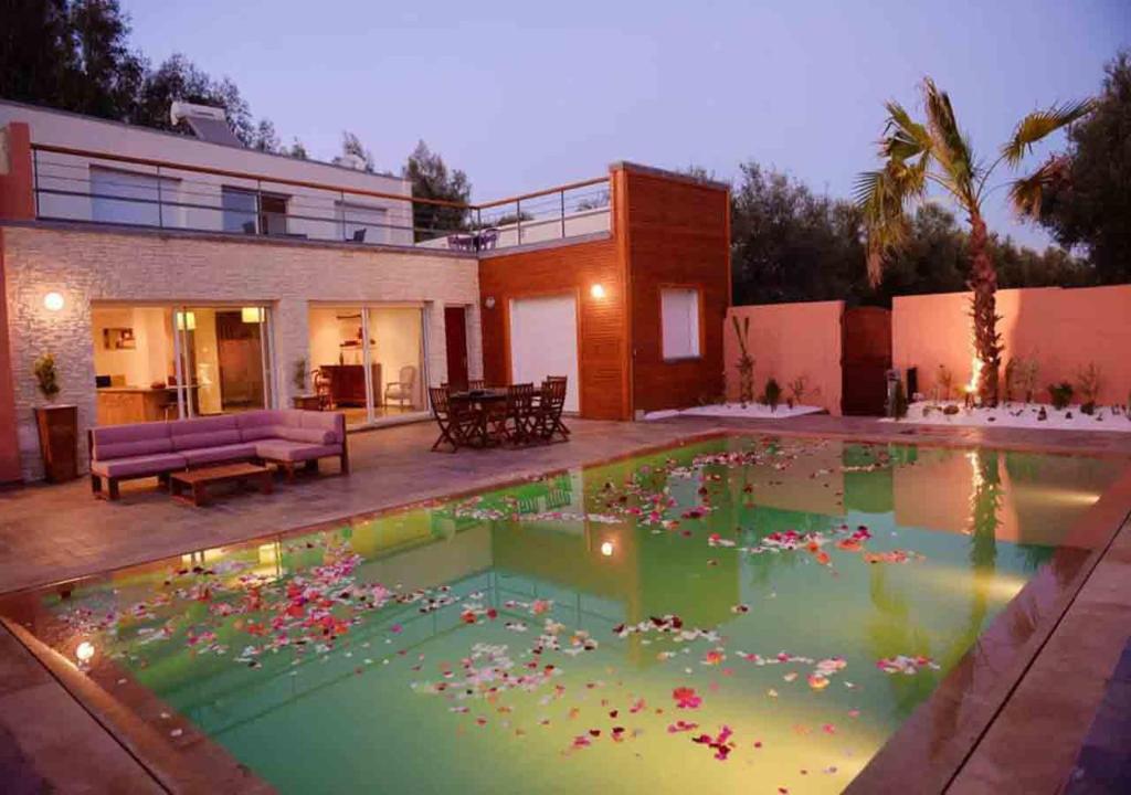 una piscina piena di fiori di fronte a una casa di Villa nahellan a Marrakech