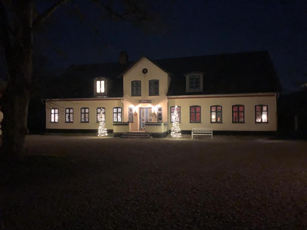 Una casa iluminada por la noche con luces de Navidad en Bremsmaj Farm Holiday, en Kværs