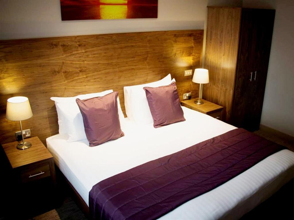 a bedroom with a large white bed with two lamps at The White Hart in Swindon