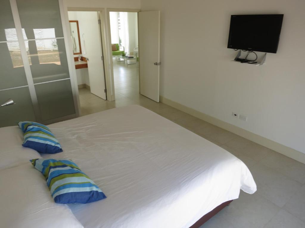 um quarto com uma grande cama branca com almofadas azuis em Tamarindo em San Andrés