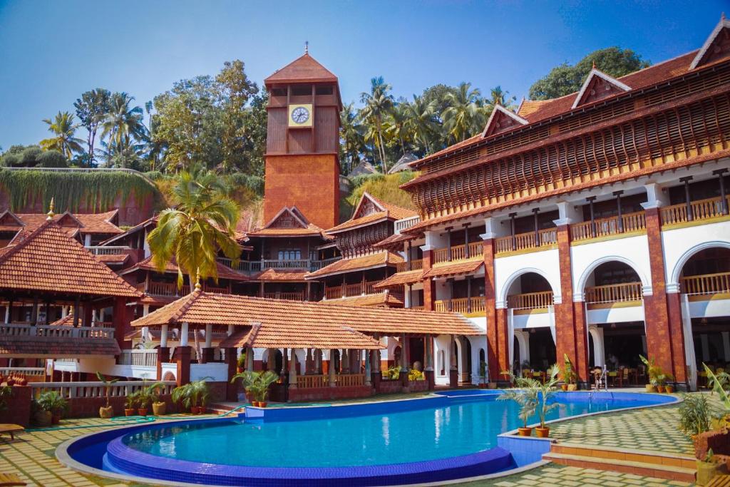 a resort with a clock tower and a swimming pool at AyurSoma Ayurveda Royal Retreat in Kovalam