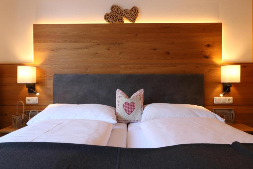 1 cama con almohadas blancas y cabecero de madera en Hotel Bräu, en Rauris