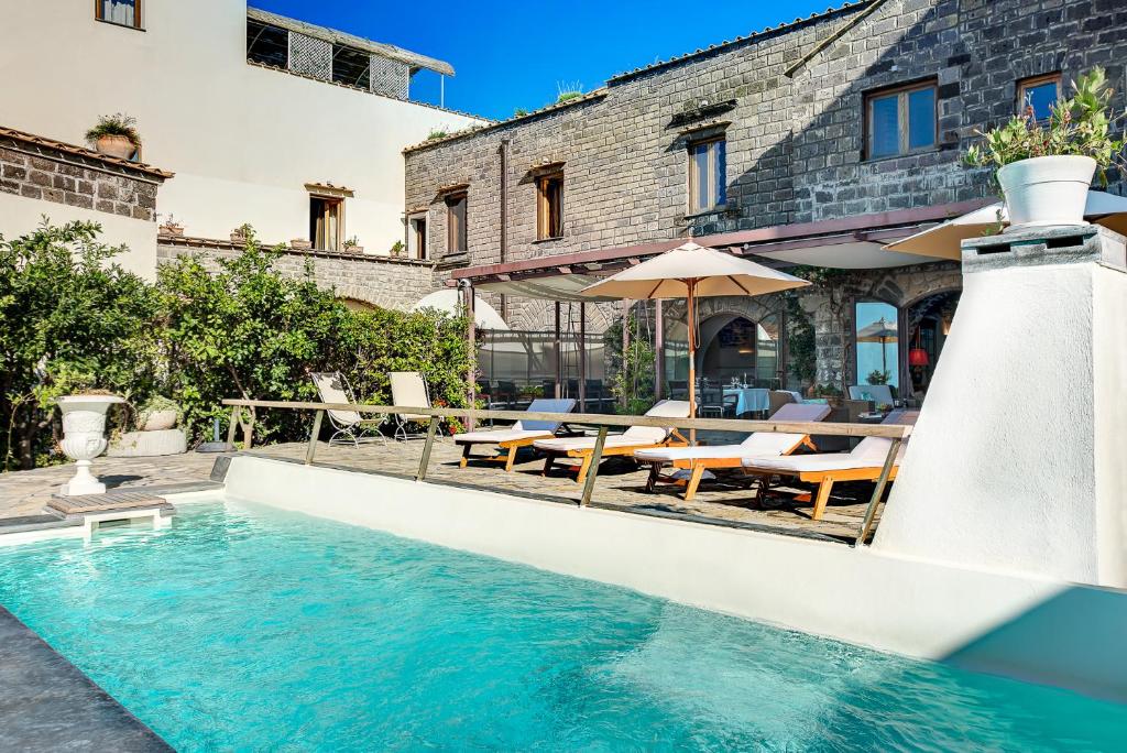 une piscine avec des tables et des chaises et un bâtiment dans l'établissement Lubra Casa Relax, à Massa Lubrense