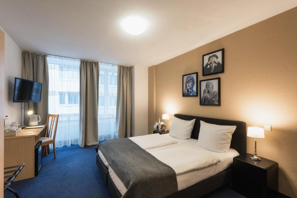 デュッセルドルフにあるシティ アパート ホテルのベッドとデスクが備わるホテルルームです。