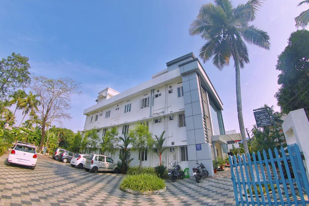 a white building with cars parked in a parking lot at Noah's Ark in Cochin