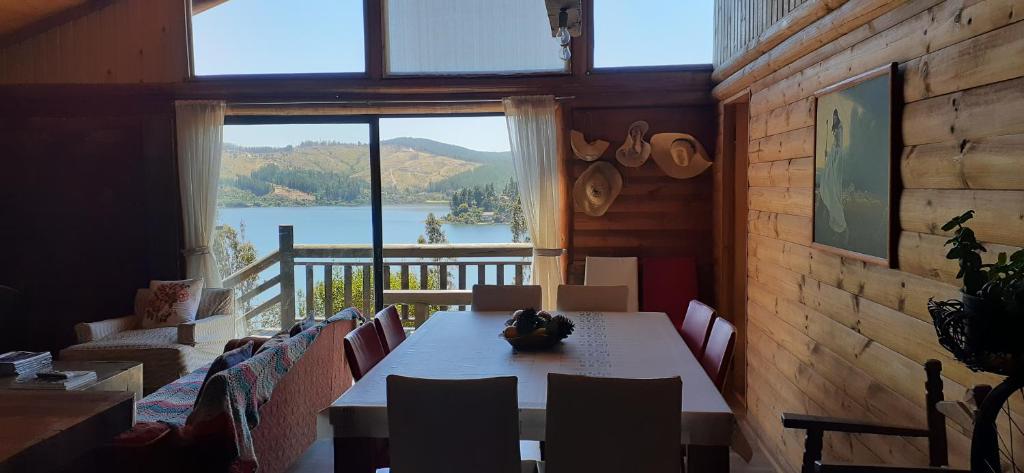 uma sala de jantar com mesa e cadeiras e uma grande janela em Casa Amanecer Vichuquén em Lago Vichuquén
