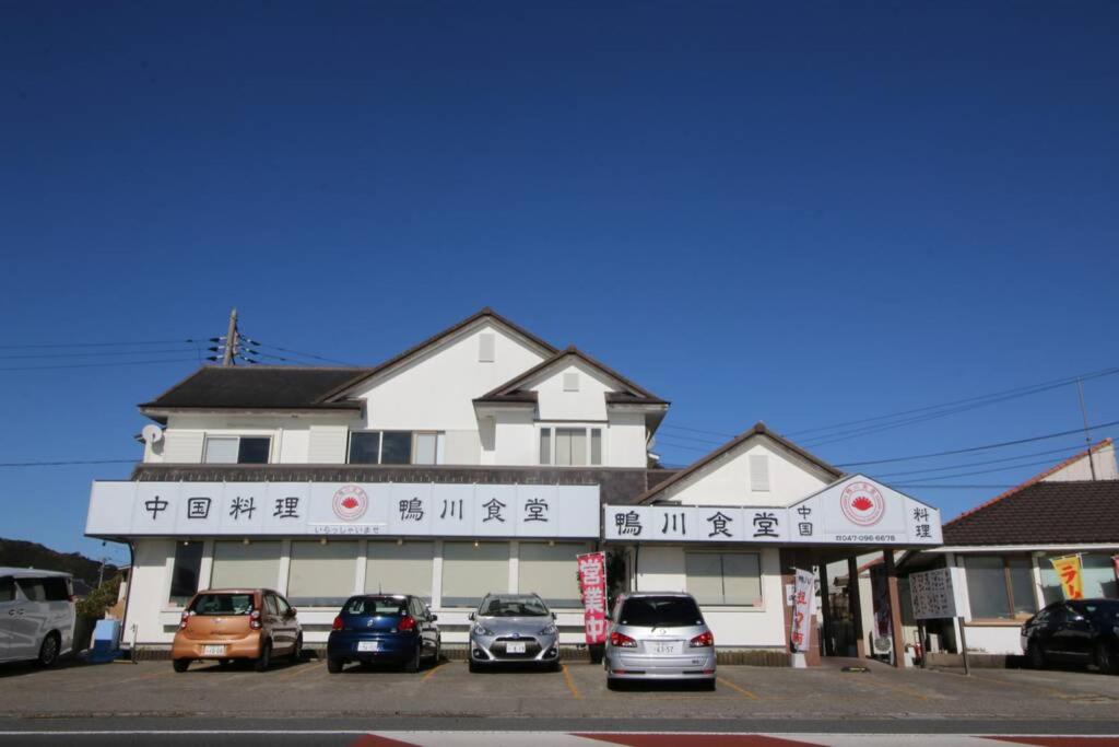 un edificio con coches estacionados frente a él en Uhome Kamogawa Villa, en Kamogawa