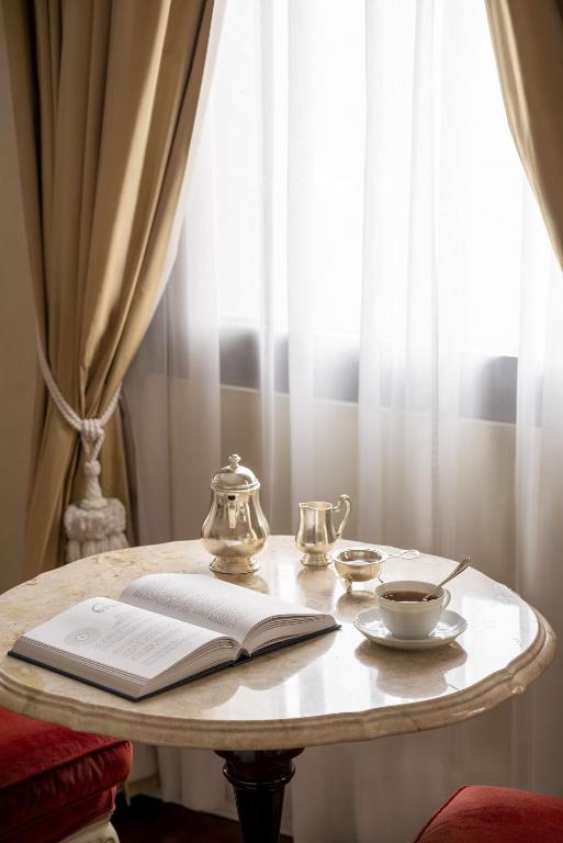 a table with an open book and a tea pot and a tea cup at Hotel Cipriani, A Belmond Hotel, Venice in Venice