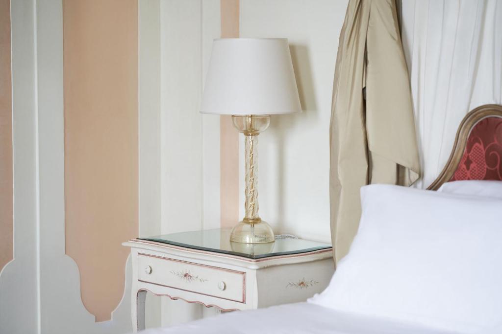 a table with a lamp on it next to a bed at Hotel Cipriani, A Belmond Hotel, Venice in Venice