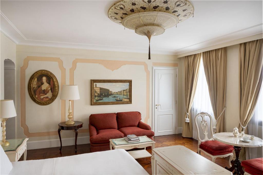 a living room with a red couch and a chandelier at Hotel Cipriani, A Belmond Hotel, Venice in Venice