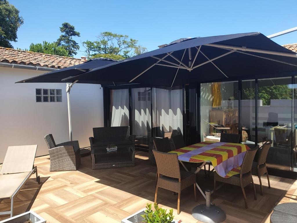 un patio con mesa y sillas bajo una sombrilla azul en Appartement le Pas Sage du Marché La Flotte, en La Flotte