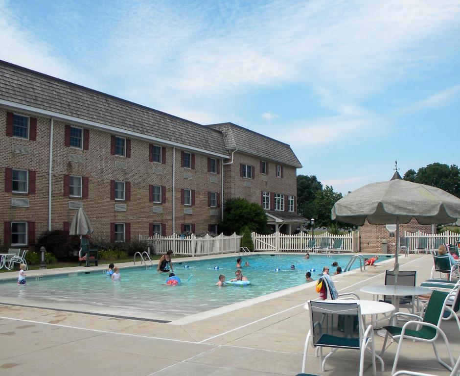 a group of people swimming in a swimming pool in front of a building at Bird-in-Hand Family Inn in Bird-in-Hand
