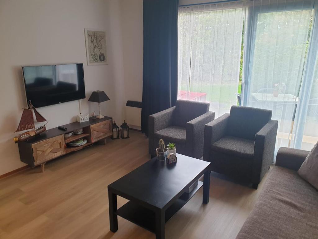 ein Wohnzimmer mit einem Sofa, 2 Stühlen und einem TV in der Unterkunft Nova Zembla in Hollum