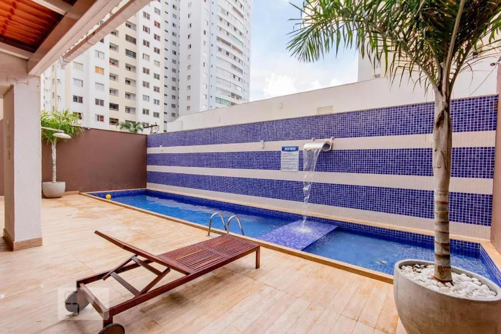 uma piscina com um banco e uma fonte em Apartamento todo climatizado 2 quartos Setor Bueno em Goiânia