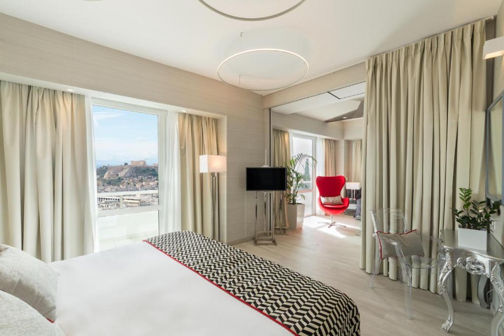 una camera d'albergo con un letto e una grande finestra di St George Lycabettus Lifestyle Hotel ad Atene
