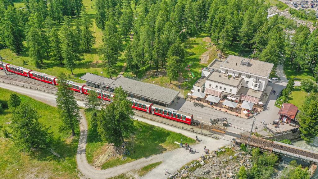 un tren rojo está en las vías cerca de una casa en Gletscher-Hotel Morteratsch en Pontresina