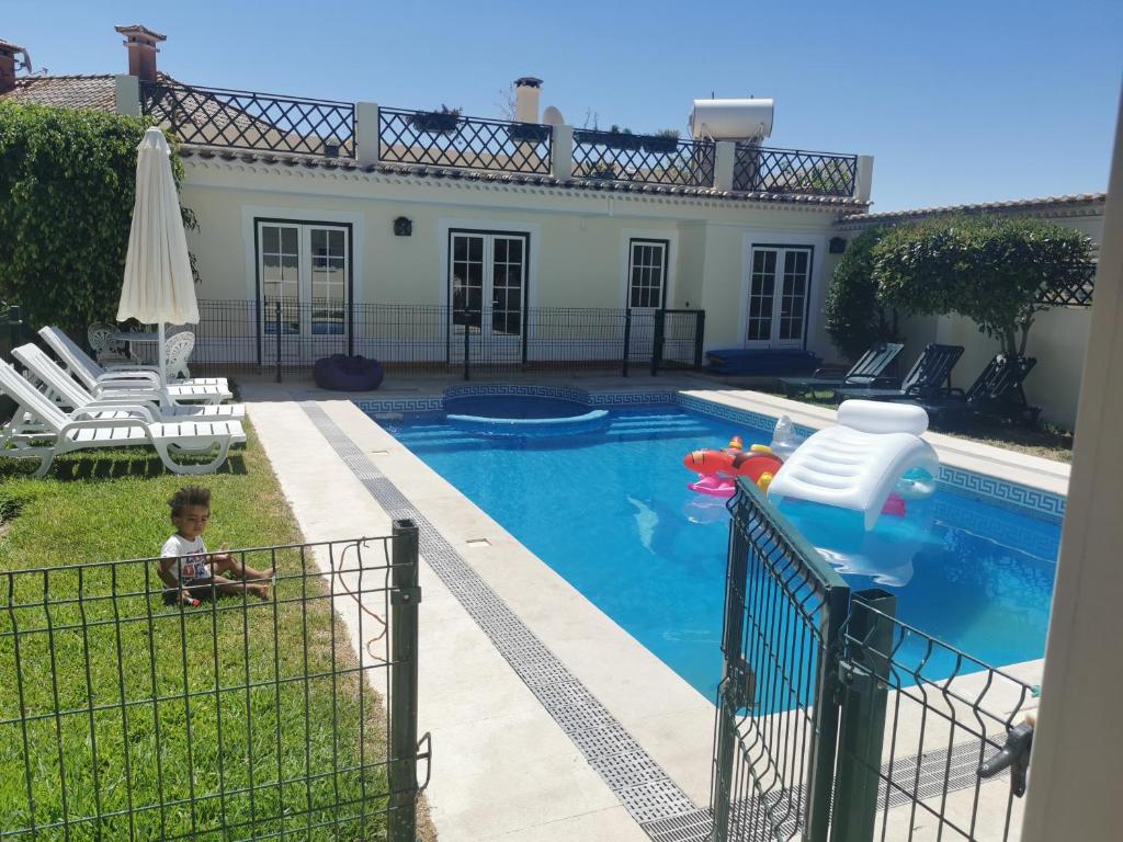 a child sitting in the grass next to a swimming pool at Férias Inesquecíveis in Carregado