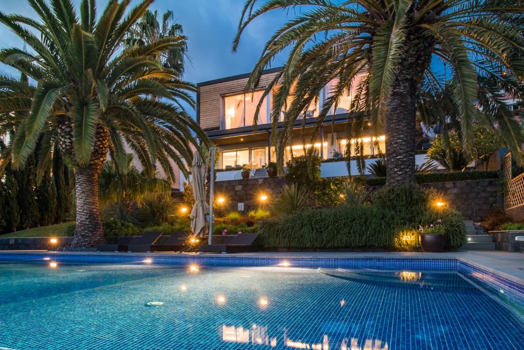 una piscina frente a un edificio con palmeras en Casa Martinhos by LovelyStay, en Caniço