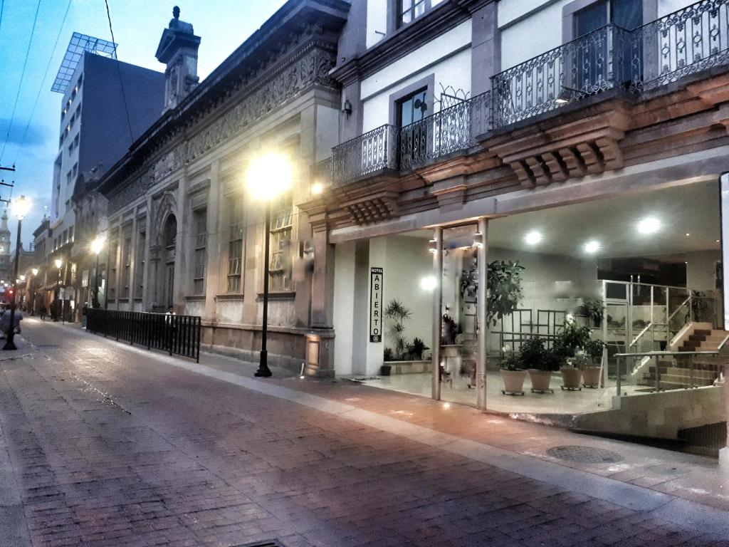 una calle de ciudad vacía por la noche con un edificio en Hotel Enterprise Inn Plaza, en León
