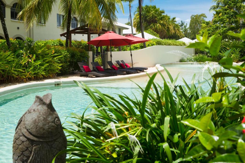 a statue of a cat in the bushes next to a swimming pool at Mango Lagoon Resort & Wellness Spa in Palm Cove