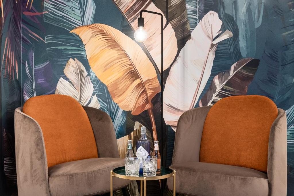 two chairs and a table in a room with a mural at Stay COOPER l Cà de Bezzi in Bolzano