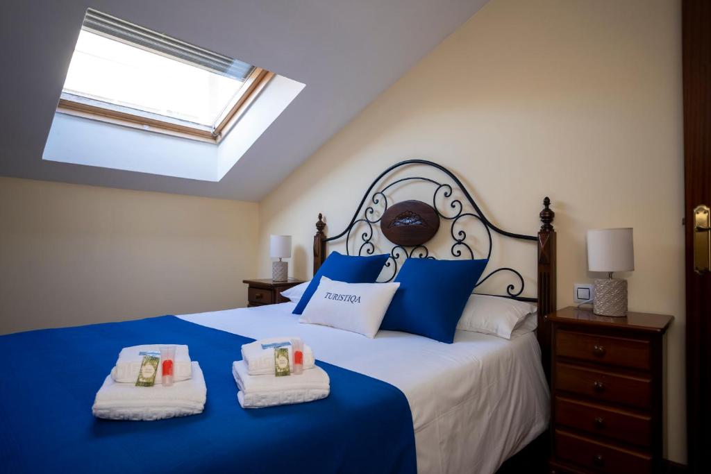 a bedroom with a blue and white bed with two towels at TuristiQA - Ático Ferrol Centro VUT-CO-02715 in Ferrol