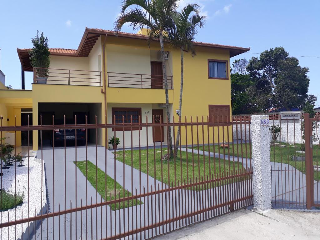 una casa amarilla con una valla delante de ella en Amplo Sobrado com Ar Condicionado a 200 metros da praia, en Florianópolis