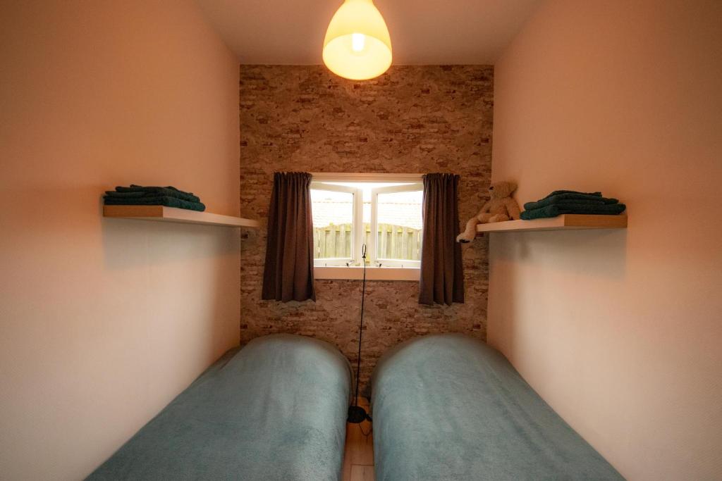 a bedroom with two beds and a window at De Cel in Nes