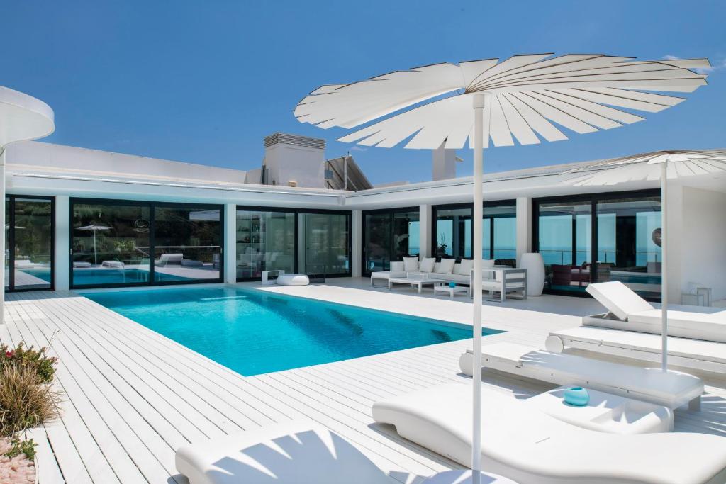una villa con piscina con sedie e ombrellone di Ibiza style Barcelona luxury Villa a Badalona